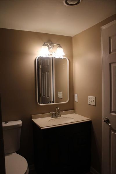 Half bathroom featuring vanity and toilet Half bathroom featuring vanity and toilet