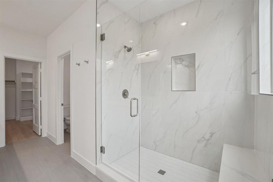 Bathroom featuring a marble finish shower and a spacious closet