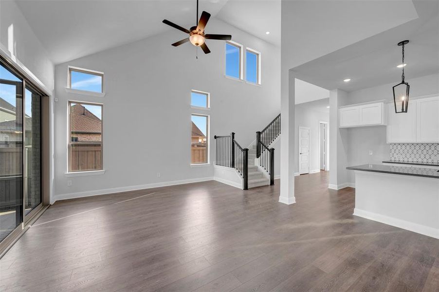 Unfurnished living room with dark wood-style floors, a ceiling fan, and lofted ceiling Unfurnished living room with dark wood-style floors, a ceiling fan, and lofted ceiling
