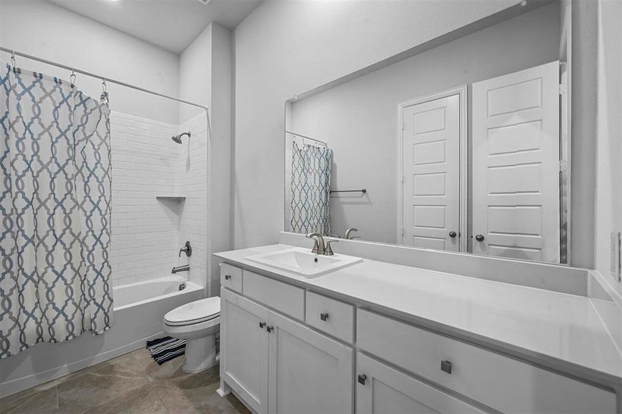 Bathroom featuring shower / bath combo, vanity, and dark tile patterned floors