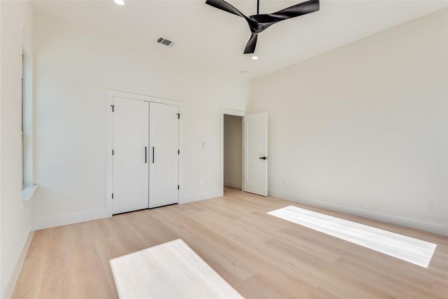 Unfurnished bedroom featuring ceiling fan, a closet, and light wood-type flooring