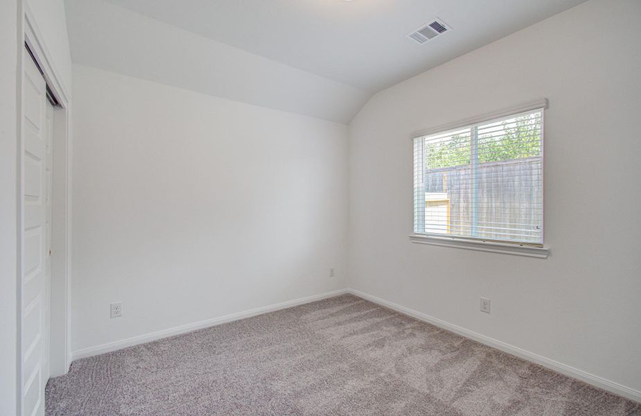 Bright and cozy bedroom featuring soft carpet, a large window for natural light, and a spacious closet.
