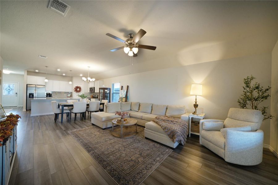 Living room with a chandelier, dark wood-style flooring, and ceiling fan