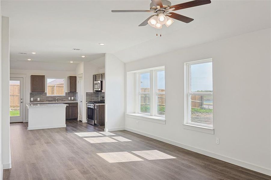 Unfurnished living room featuring ceiling fan, lofted ceiling, and light hardwood / wood-style flooring