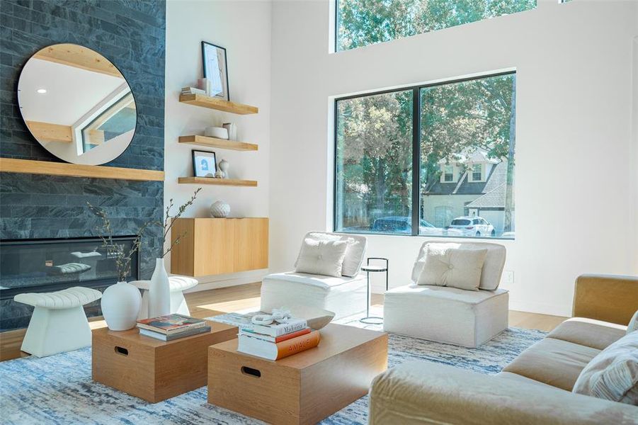 Living room with hardwood / wood-style flooring, a towering ceiling, and a large fireplace