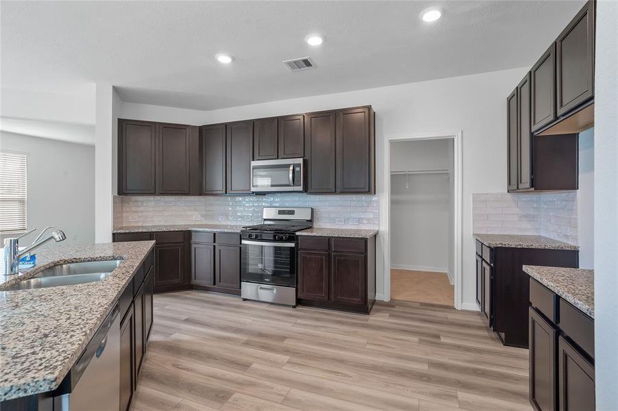 This kitchen is by far any chef’s dream! This spacious kitchen features high ceilings, dark stained wood cabinets, granite countertops, SS appliances, modern tile backsplash, recessed lighting, extended counter space, granite kitchen island with double sink and space for breakfast bar, and a walk-in pantry all overlooking your huge family room.