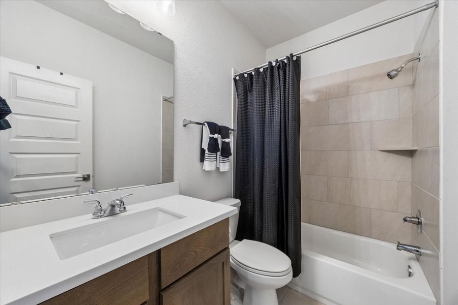 Full upstairs bathroom with a quartz vanity, tiled tub/shower, and modern finishes