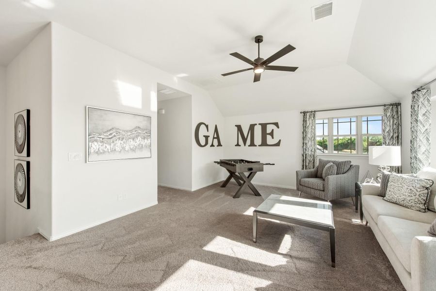 Game room with vaulted ceiling, ceiling fan, foosball table, and seating area on carpet