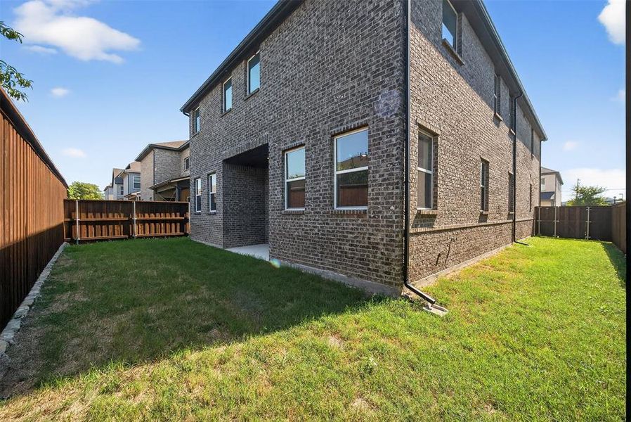 View of side of home with brick siding, a fenced backyard, and a patio area