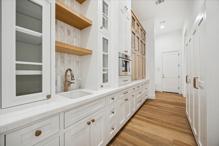 A well-appointed butler’s pantry with ample storage, prep sink, and Thermador built-in coffee system. The space also includes the Thermador MicroDrawer microwave and serves as a functional extension of the main kitchen.