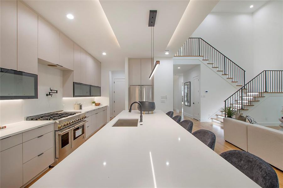 Kitchen featuring light hardwood / wood-style floors, hanging light fixtures, high quality appliances, and sink