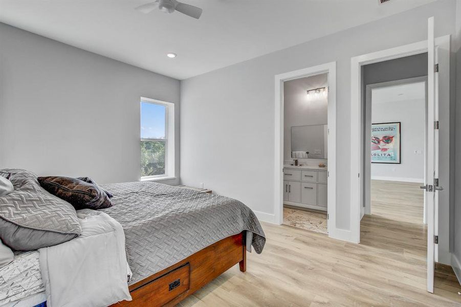 Bedroom featuring light wood-type flooring, a ceiling fan, ensuite bathroom, and recessed lighting
