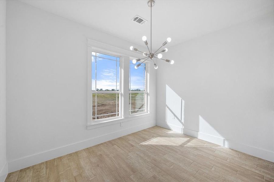 Unfurnished dining area with light hardwood / wood-style floors, a notable chandelier, and a wealth of natural light