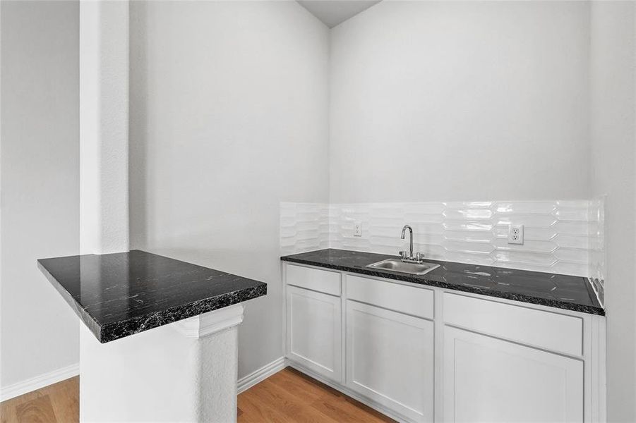 Kitchen with white cabinets, light wood-style flooring, a peninsula, and dark stone countertops Kitchen with white cabinets, light wood-style flooring, a peninsula, and dark stone countertops