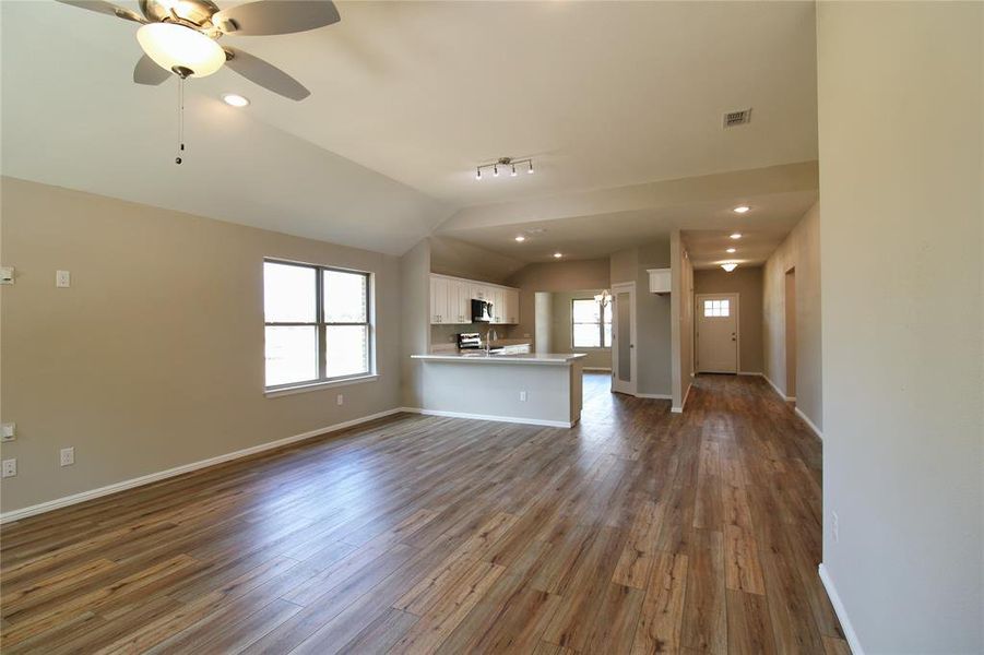 Unfurnished living room featuring dark wood-style floors, a ceiling fan, vaulted ceiling, and recessed lighting