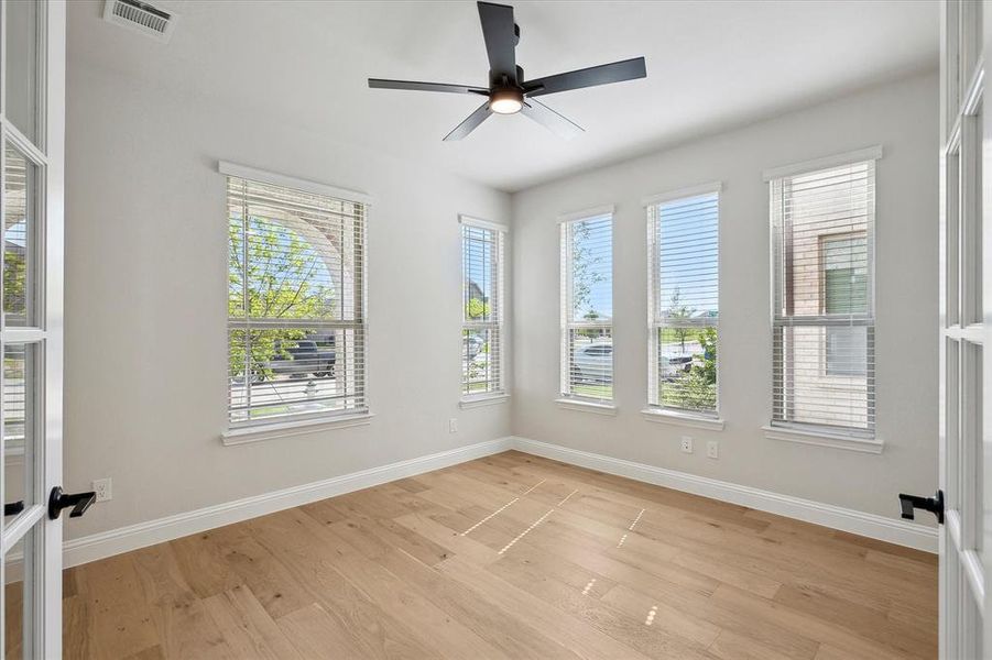 Unfurnished room featuring healthy amount of natural light, light wood-type flooring, baseboards, and ceiling fan
