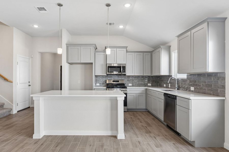 Vaulted ceilings and wood-look tile flooring enhance this modern culinary space.