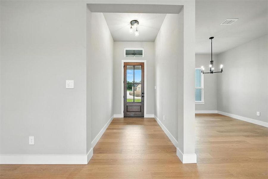 Entrance foyer featuring a chandelier and light wood-style floors Entrance foyer featuring a chandelier and light wood-style floors