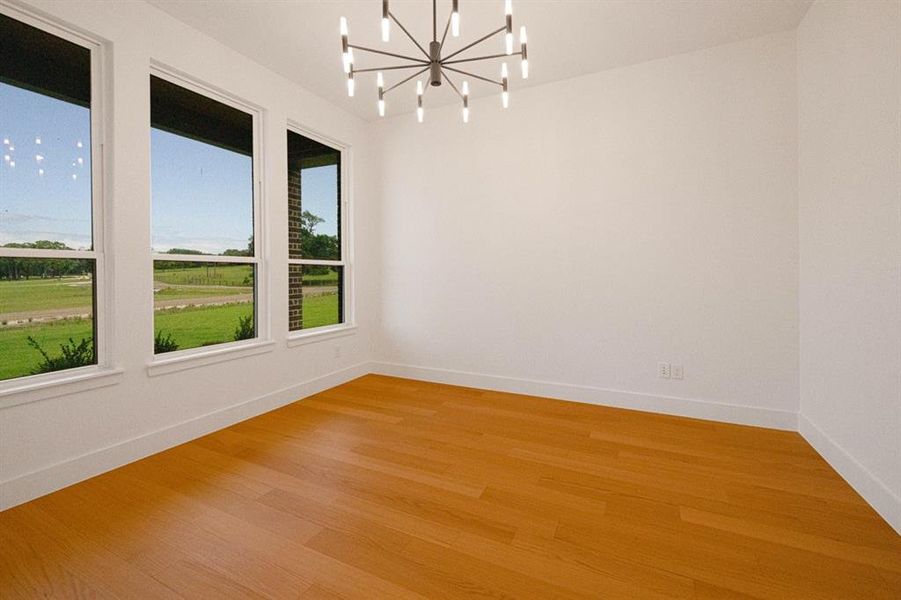 Unfurnished room with suspended lighting and light wood-type flooring