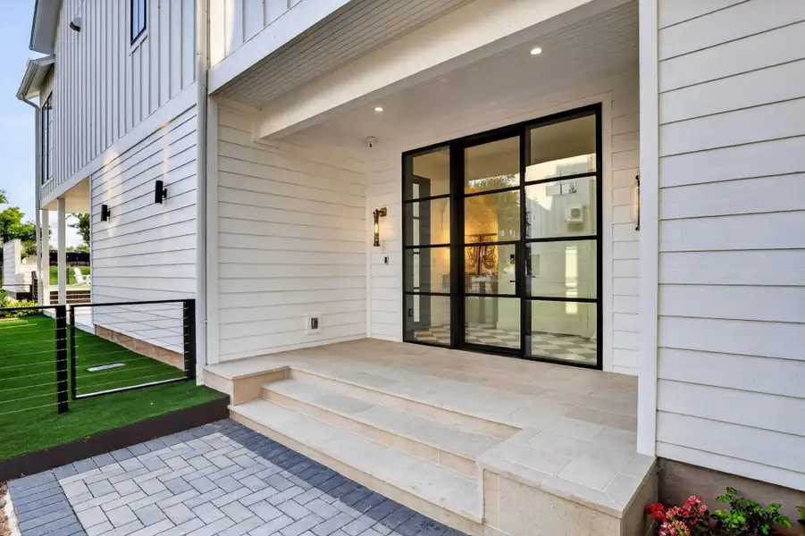 An inviting front entry features modern black-framed glass doors and a pristine paved walkway, offering sleek curb appeal. An inviting front entry features modern black-framed glass doors and a pristine paved walkway, offering sleek curb appeal.