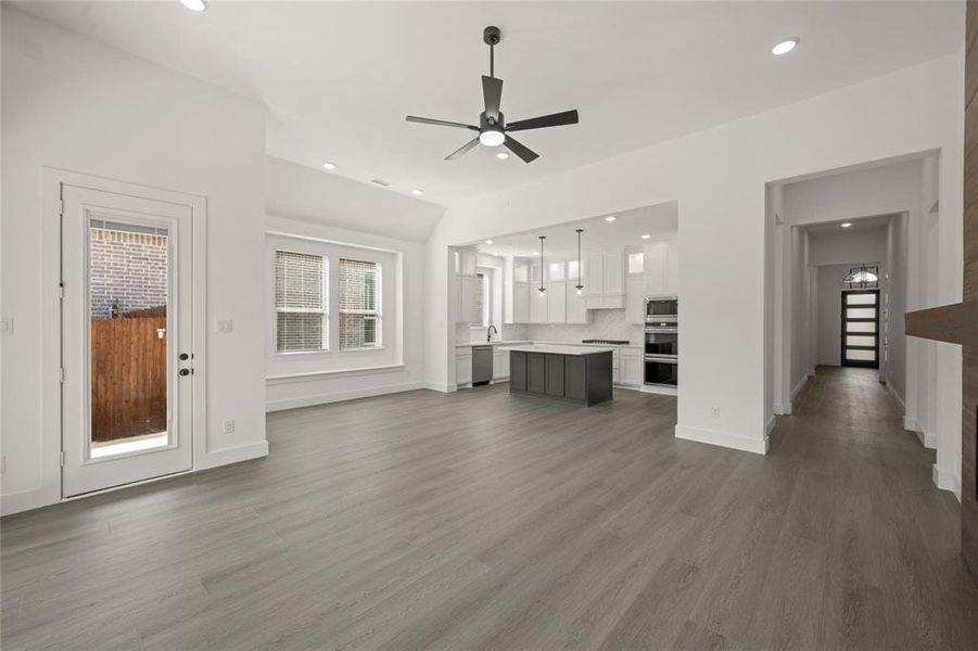 Unfurnished living room featuring ceiling fan, dark wood-style flooring, and recessed lighting