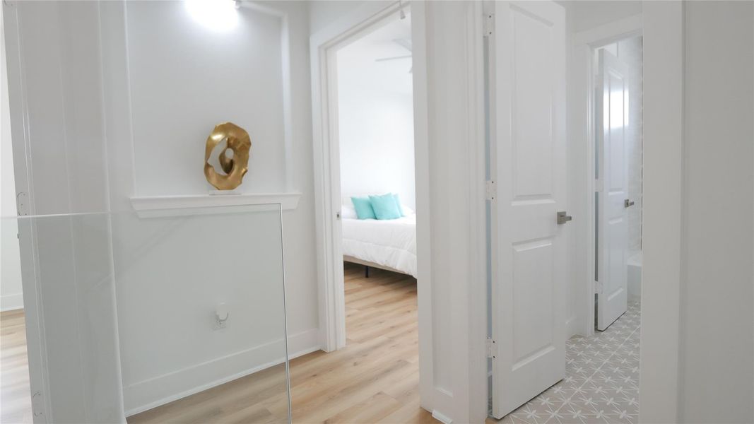 This bright and modern hallway features light wood flooring and access to a bedroom and a bathroom with stylish tile flooring. The clean design and neutral colors create an inviting atmosphere. This bright and modern hallway features light wood flooring and access to a bedroom and a bathroom with stylish tile flooring. The clean design and neutral colors create an inviting atmosphere.