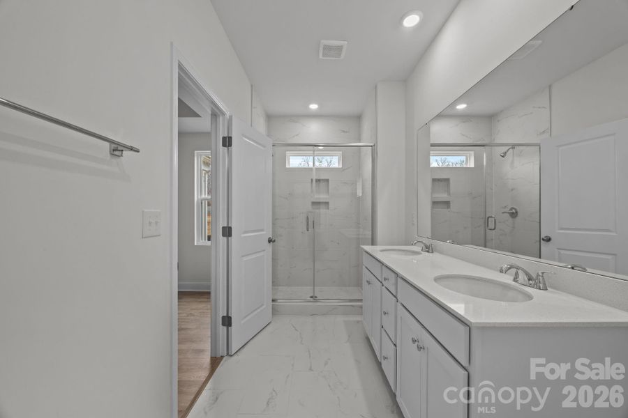 Primary bath with tiled shower, floor and quartz countertops