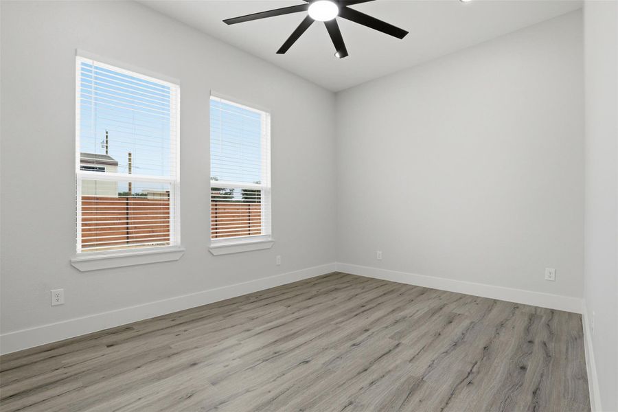 Spacious room featuring two large windows with blinds, wood-finish flooring, a ceiling fan with integrated lighting, and recessed ceiling lights