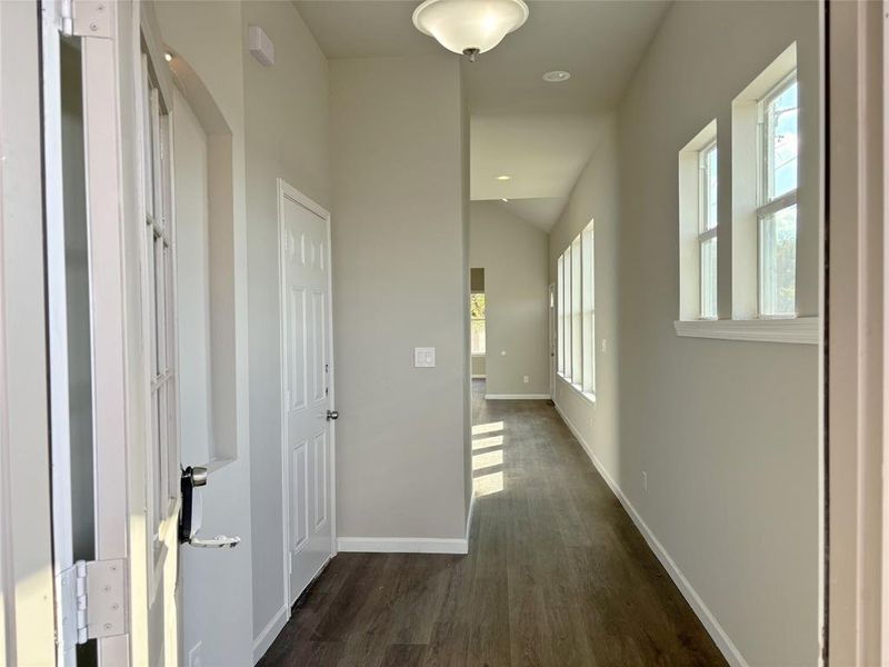 Hallway with dark wood-style flooring, recessed lighting, and vaulted ceiling