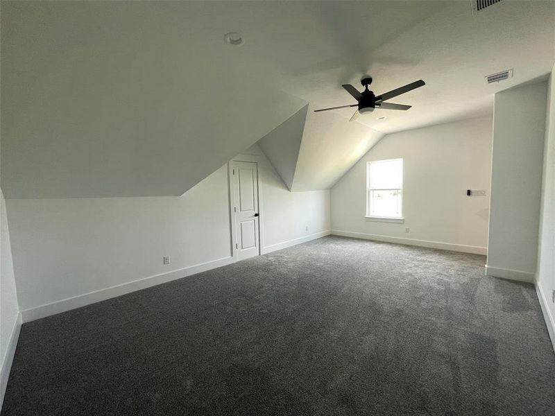 Additional living space featuring vaulted ceiling, dark colored carpet, and ceiling fan Additional living space featuring vaulted ceiling, dark colored carpet, and ceiling fan