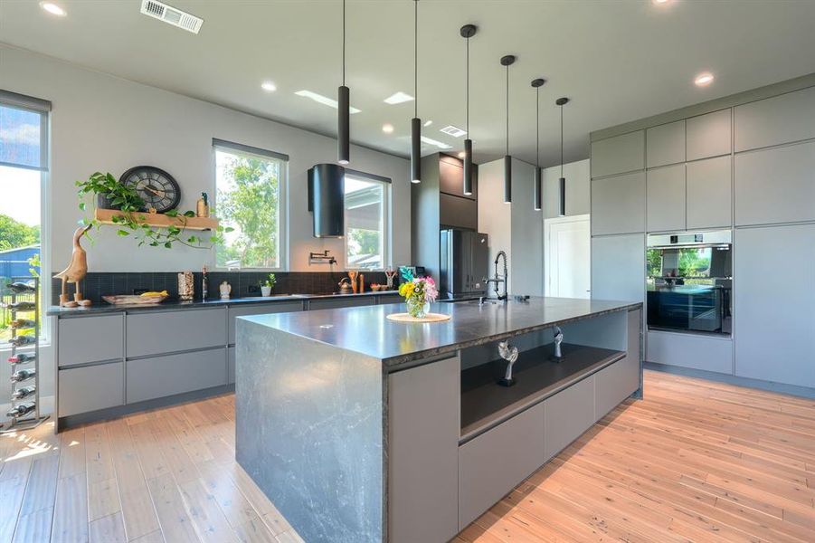 Kitchen with gray cabinetry, modern cabinets, open shelves, a center island with sink, and recessed lighting Kitchen with gray cabinetry, modern cabinets, open shelves, a center island with sink, and recessed lighting