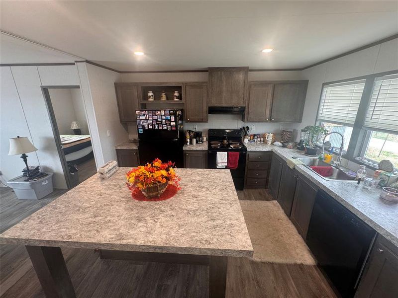 Kitchen featuring black appliances, light countertops, dark wood finish cabinetry, recessed lighting, and range hood Kitchen featuring black appliances, light countertops, dark wood finish cabinetry, recessed lighting, and range hood