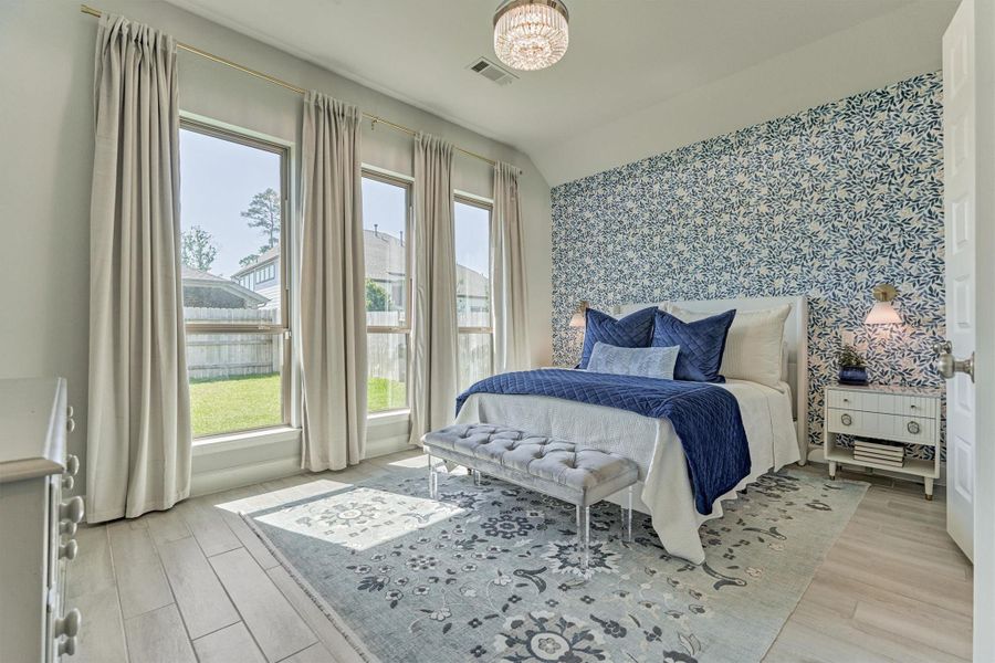 Primary bedroom with designer Rifle Paper Co. accent wall, fandelier ceiling fan, West Elm sconces on 3 way bedside switches and wood-like tile.