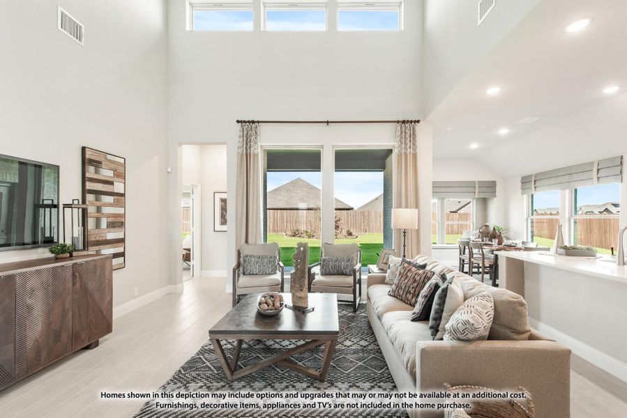 Open living room with two-story ceilings, large windows, neutral sofa, and backyard views