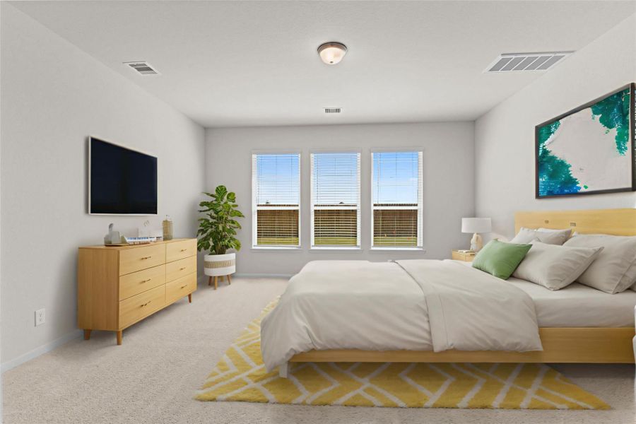 Private primary bedroom located on the first floor featuring plush carpeting and large windows that allow natural light to fill the room. This spacious retreat offers comfort and privacy while being conveniently located near the main living areas. **Virtually Staged**