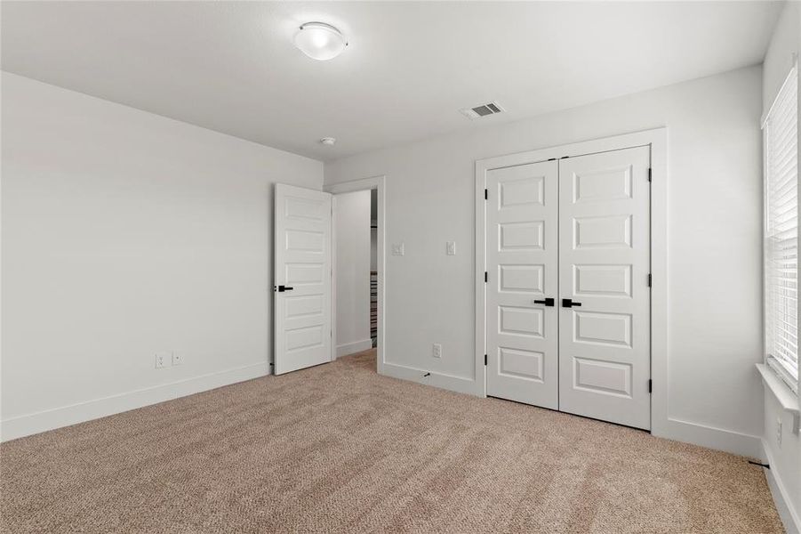 Unfurnished bedroom with a closet and light carpet Unfurnished bedroom with a closet and light carpet