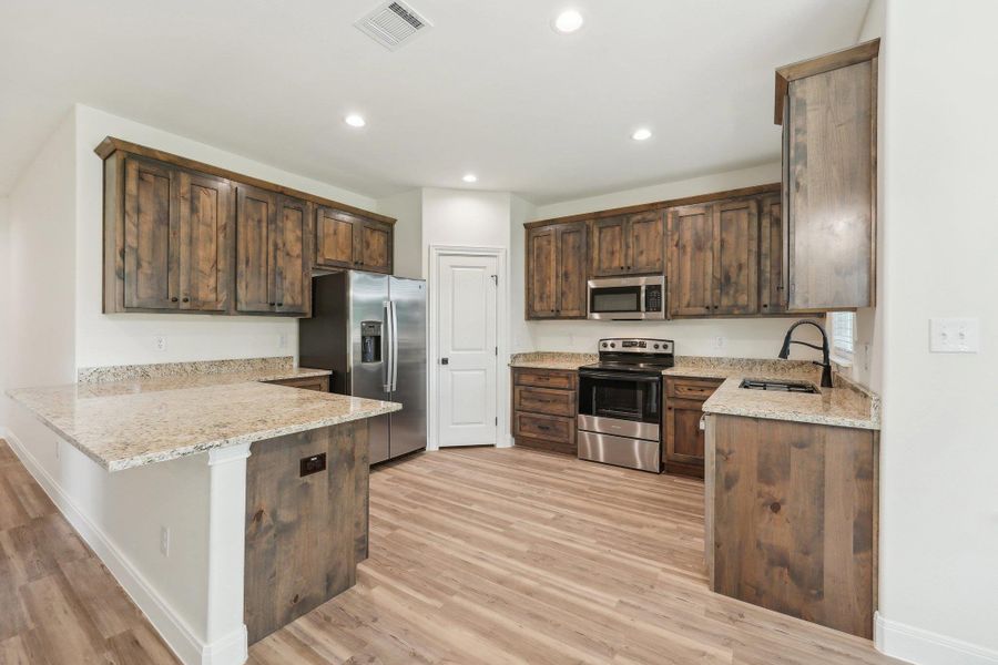Kitchen with a peninsula, Vinyl Wood Plank floor, appliances with stainless steel finishes, and a sink Kitchen with a peninsula, Vinyl Wood Plank floor, appliances with stainless steel finishes, and a sink