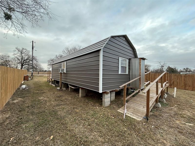 View of side of home with a gambrel roof and a wooden deck
