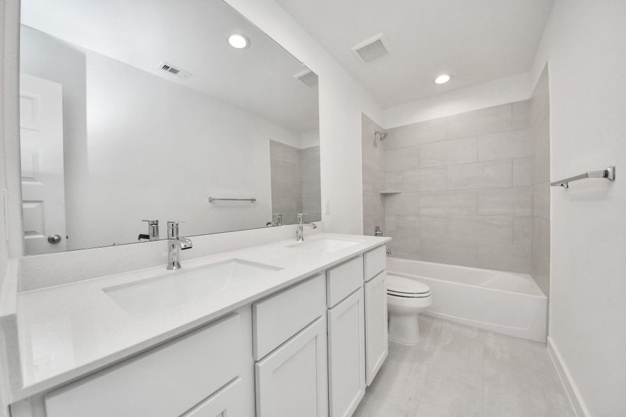 Secondary bath features tile flooring, bath/shower combo with tile surround, light stained wood cabinets, beautiful light countertop. Secondary bath features tile flooring, bath/shower combo with tile surround, light stained wood cabinets, beautiful light countertop.