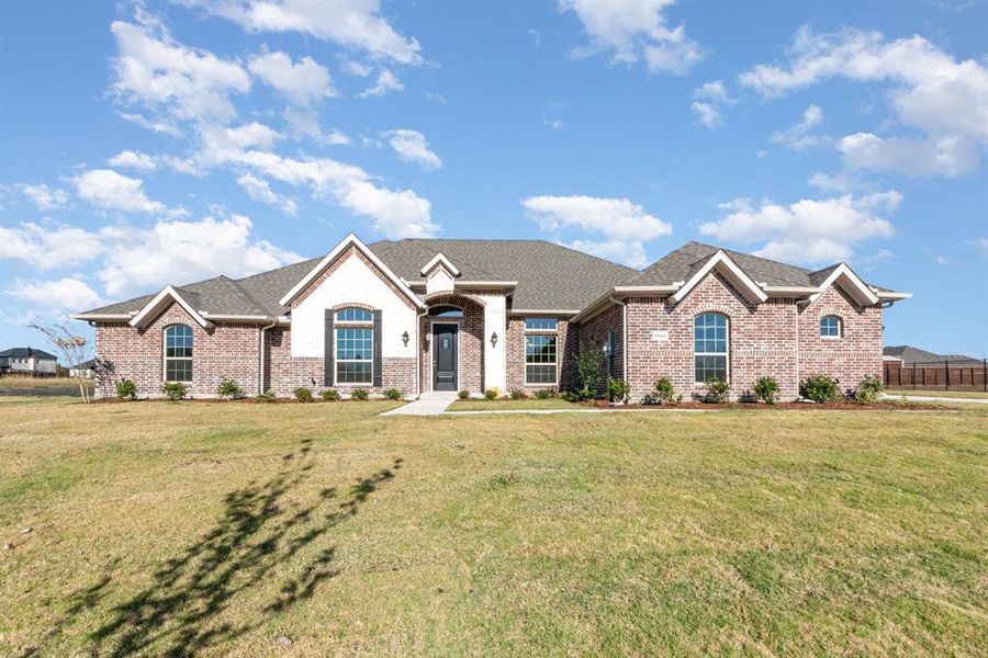View of front of home featuring brick siding, a shingled roof, and a front lawn