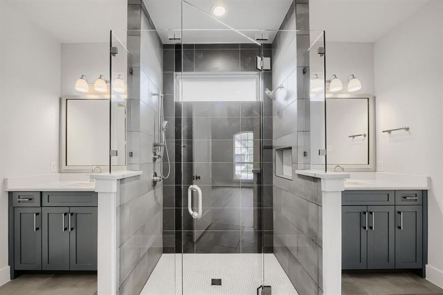 Frameless glass shower enclosure with white hex tile flooring and dual shower fixtures