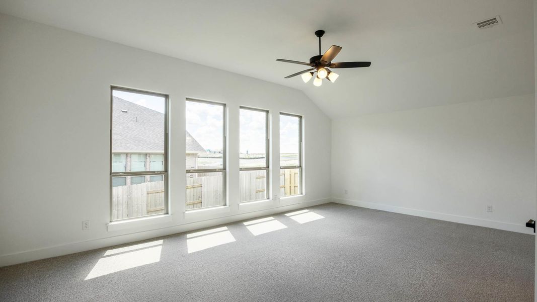 Carpeted spare room with vaulted ceiling and ceiling fan Carpeted spare room with vaulted ceiling and ceiling fan