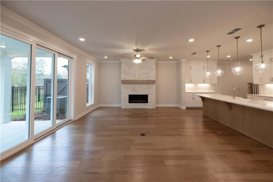 Unfurnished living room featuring ornamental molding, dark wood finished floors, a fireplace, ceiling fan, and recessed lighting