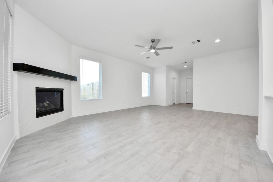 Family room flooded with natural light through the expansive windows.  The premium tile flooring adds a touch of luxury to the space, creating the perfect setting for relaxing moments and cherished gatherings with loved ones. Sample photo of completed home with similar floor plan. Actual colors and selections may vary.