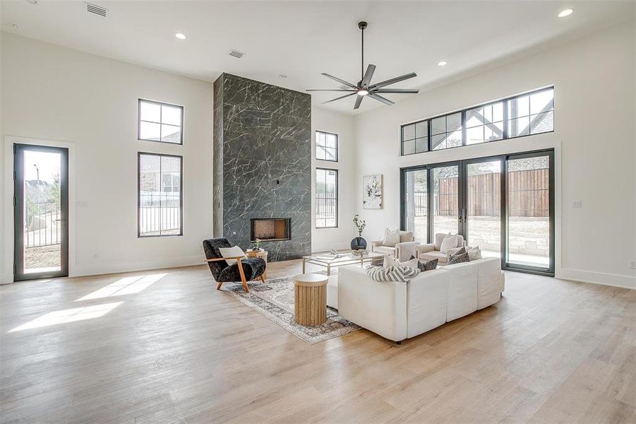 Living area featuring french doors, a healthy amount of sunlight, light wood-style flooring, and a high end fireplace