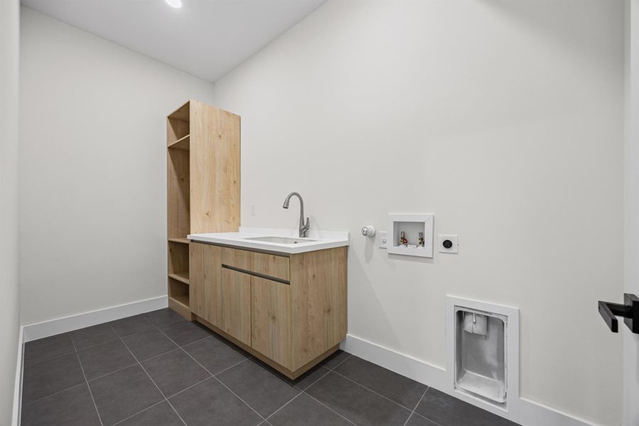 Laundry room with dark tile patterned flooring, hookup for a washing machine, hookup for an electric dryer, and cabinet space