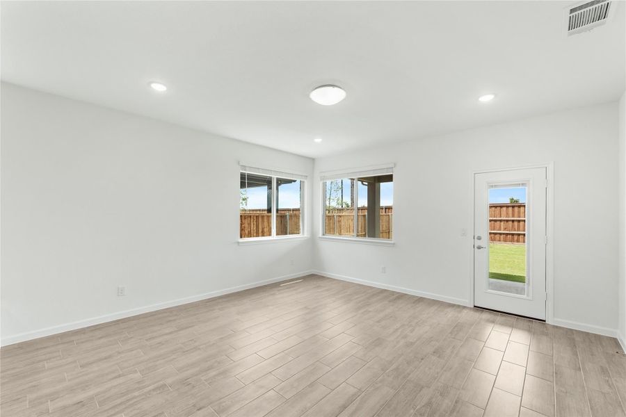 Empty room with light wood-look floors, white walls, and a glass door leading to a fenced backyard