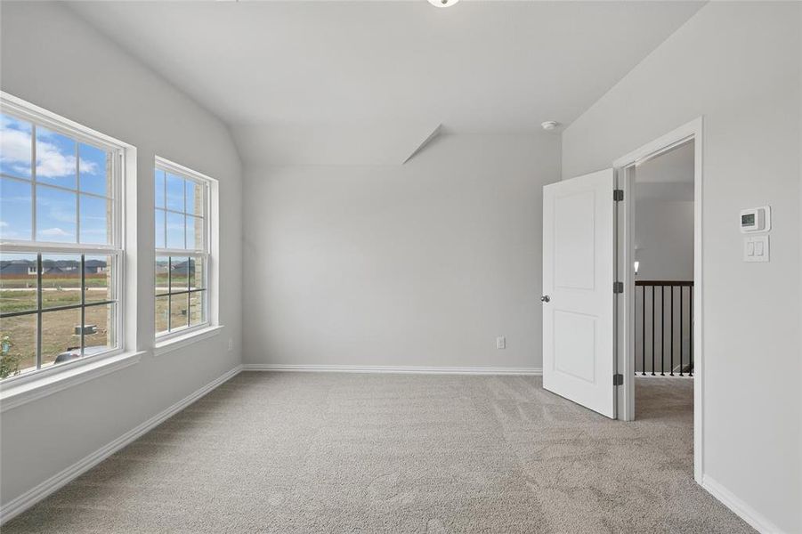 Empty room with light colored carpet and vaulted ceiling