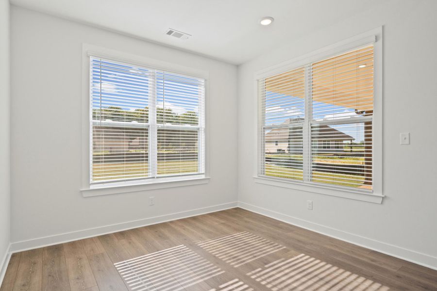 Expansive windows with installed blinds, recessed ceiling lighting, and wood-finish flooring Expansive windows with installed blinds, recessed ceiling lighting, and wood-finish flooring