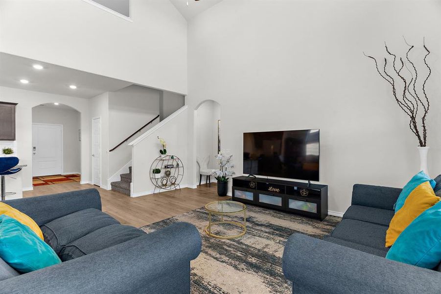 Living area with stairs, recessed lighting, baseboards, arched walkways, and wood finished floors